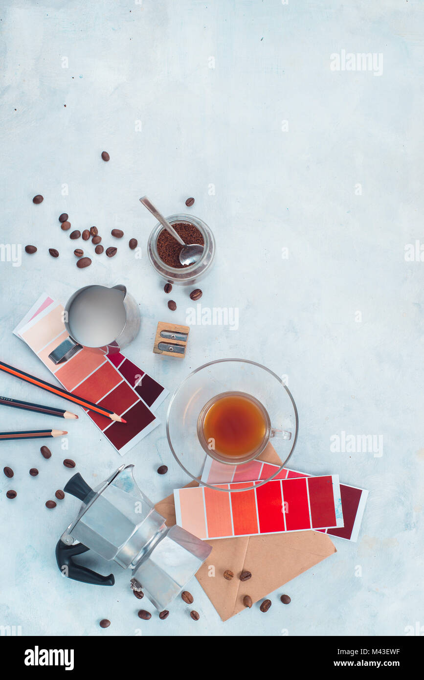 Color swatches of red and marsala in designer workplace. Moka coffee pot, color palettes, pencils, notes and coffee cups. Inspiration in alternative c Stock Photo