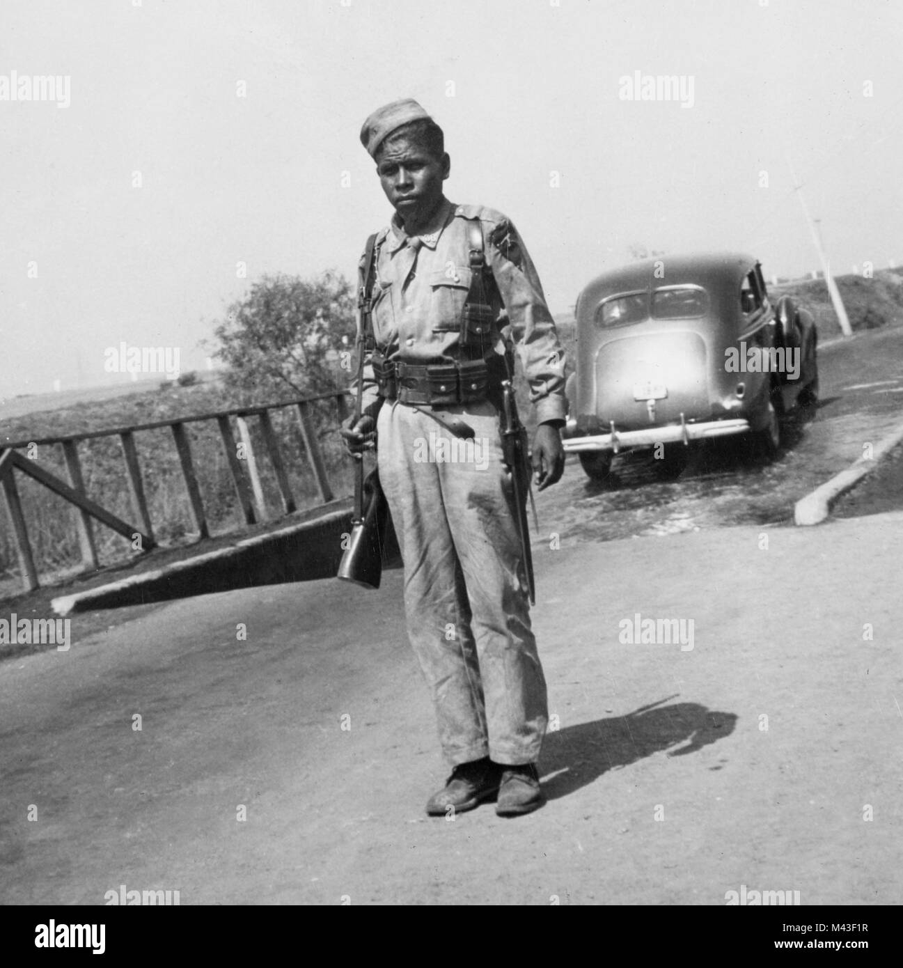 Border guard in Mexico screening cars for foot and mouth disease, ca. 1947.  Cars drive through solution in background to prevent the spread of the disease. Passengers are also required to walk through the solution. Stock Photo