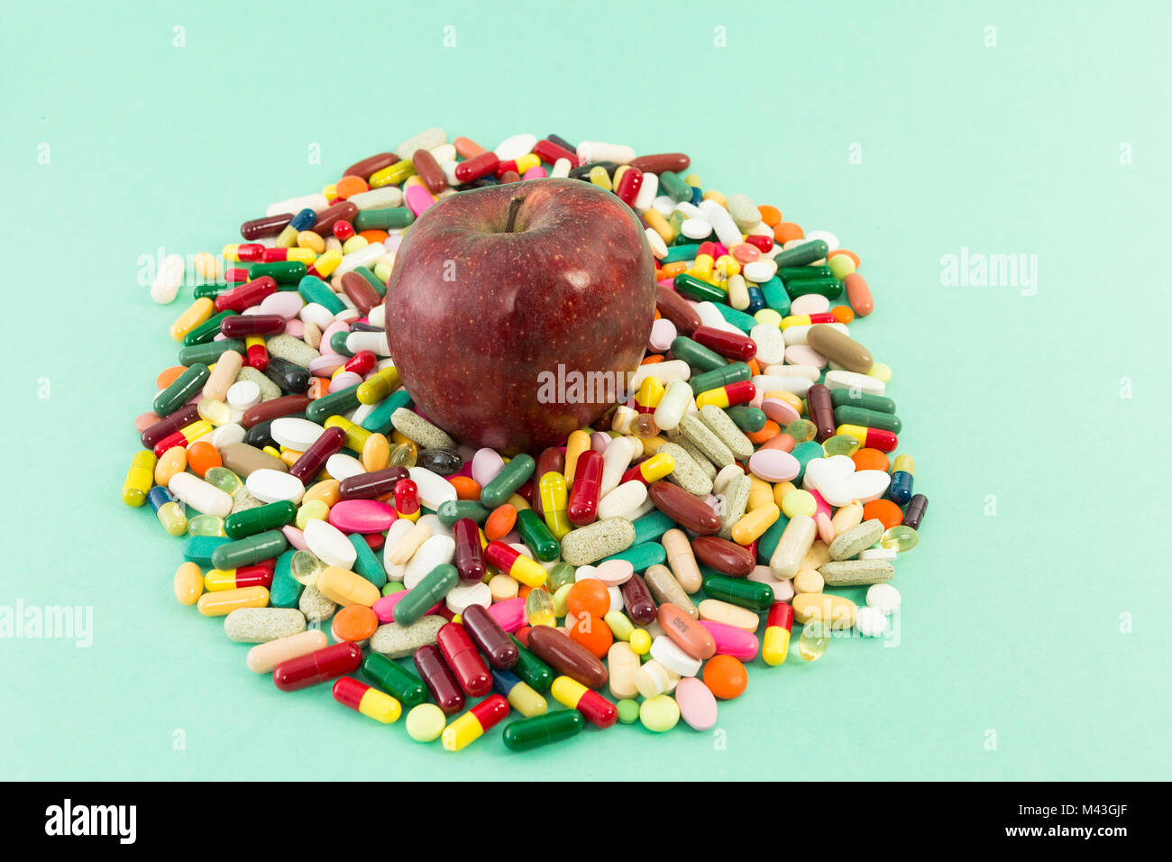 Red delicious apple on a pile of pills or tablets as natural vitamins