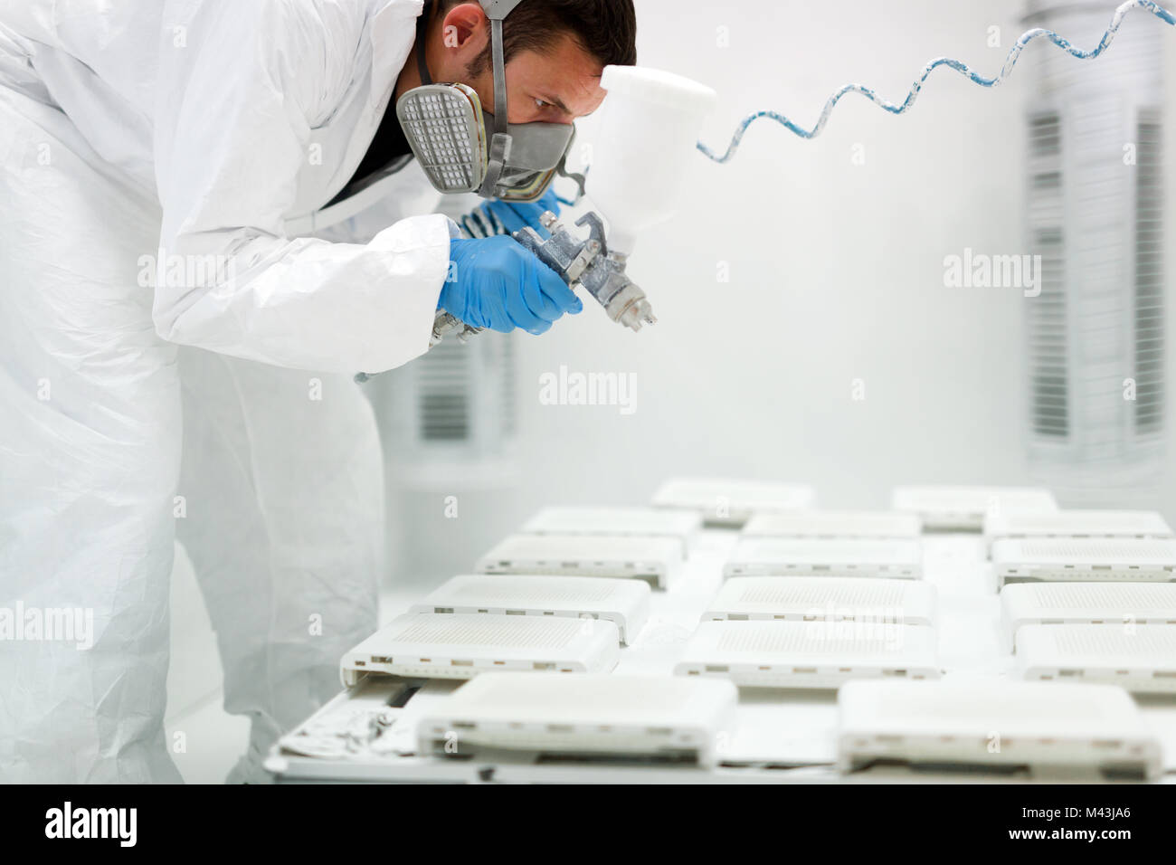 Painter using airbrush to paint wearing protective clothing Stock Photo