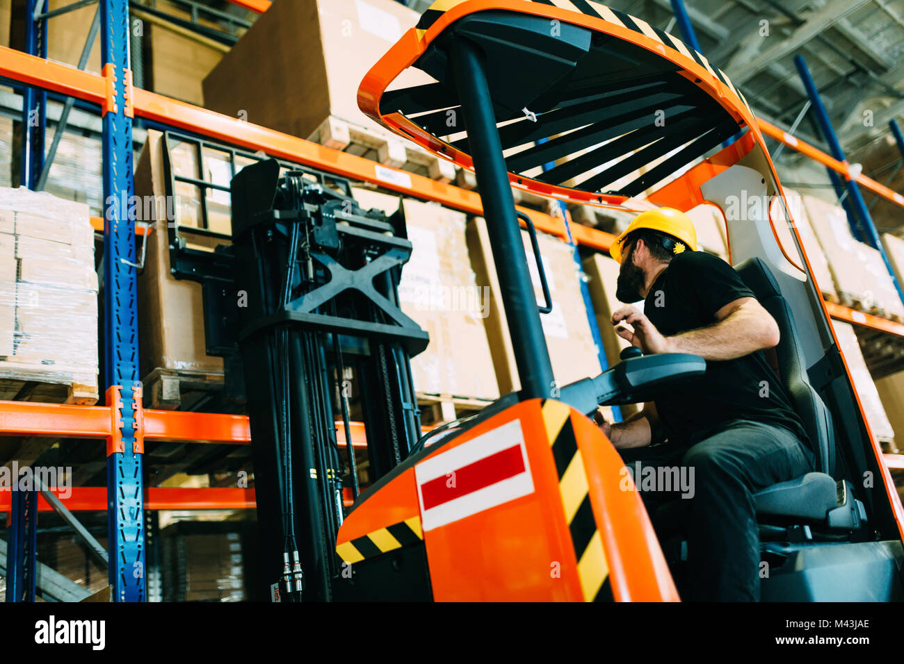 Warehouse worker doing logistics work with forklift loader Stock Photo