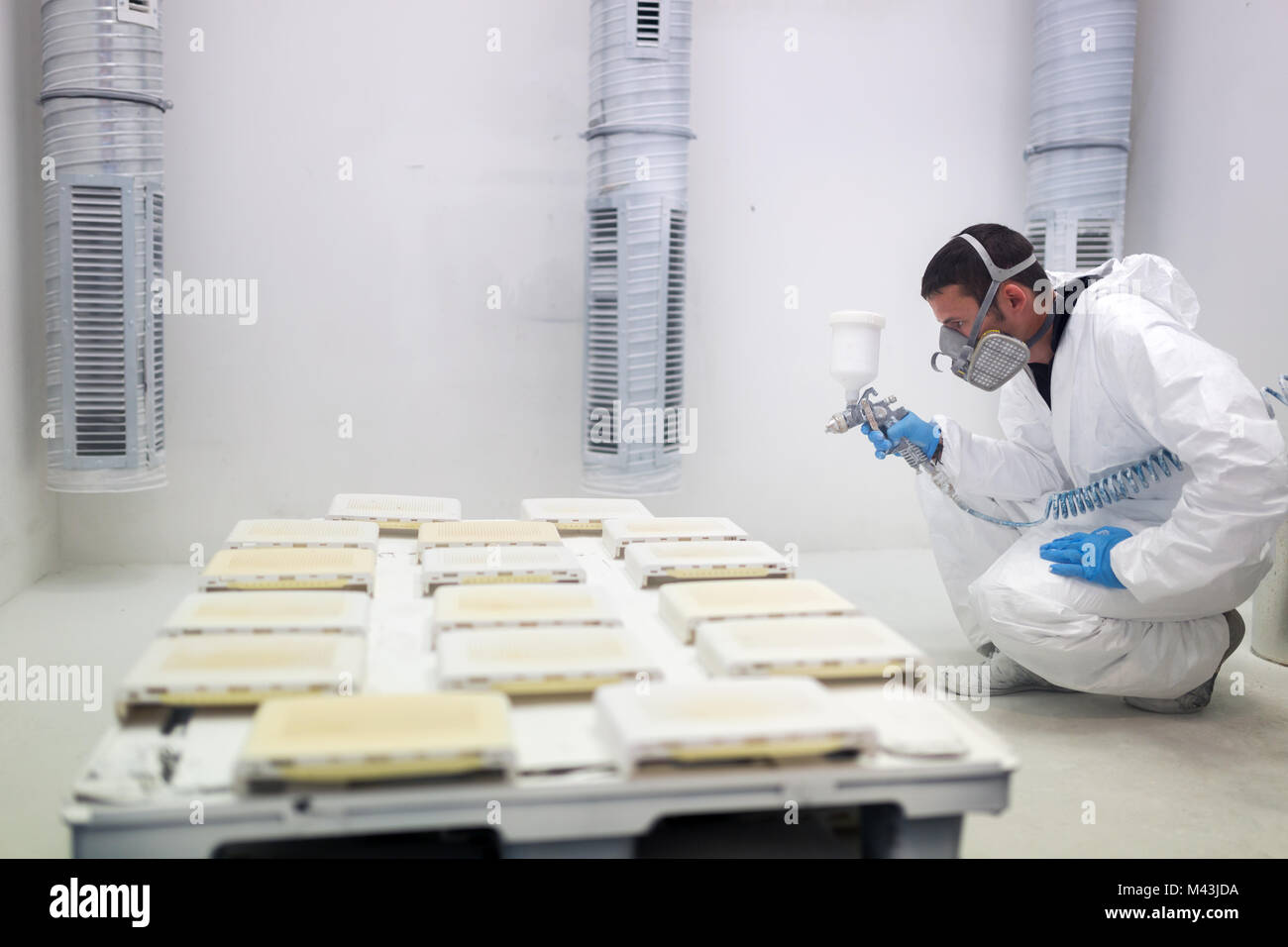 Painter using airbrush to paint wearing protective clothing Stock Photo