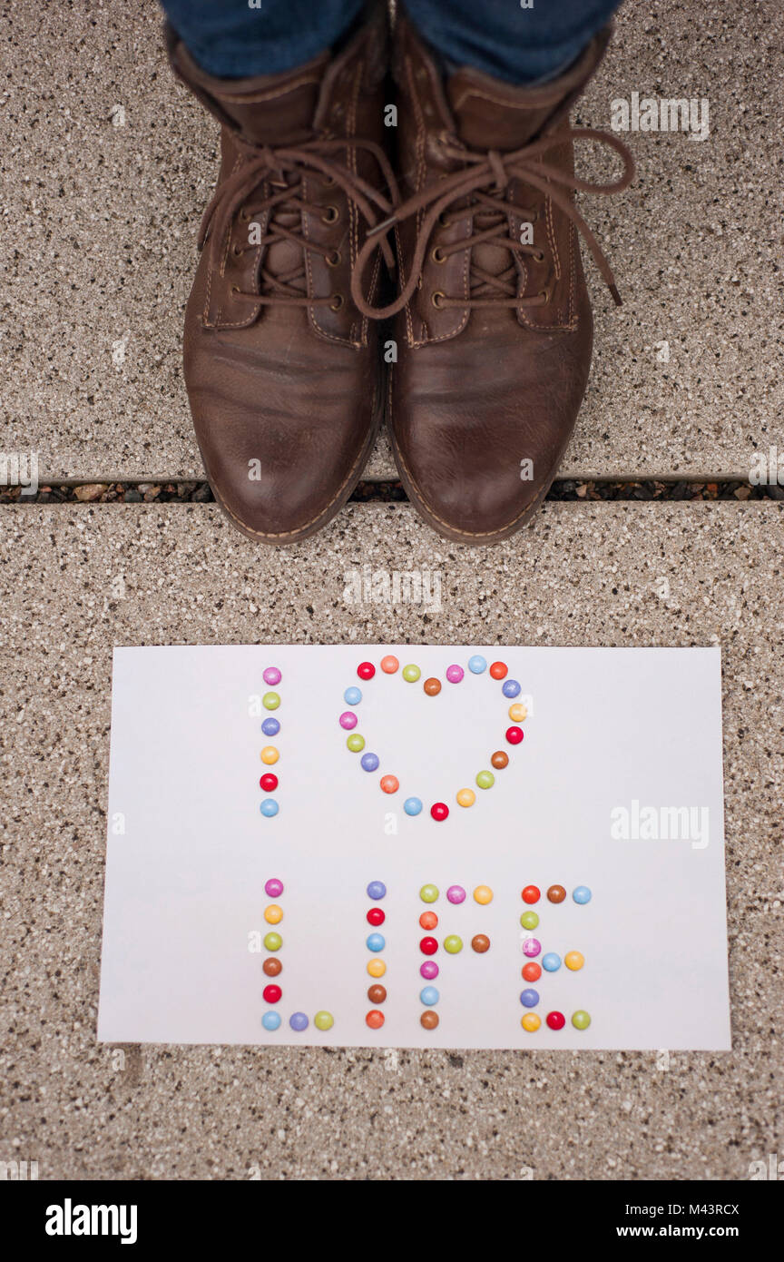 paper with words "I love life" on the ground and woman with a brown shoes near it Stock Photo
