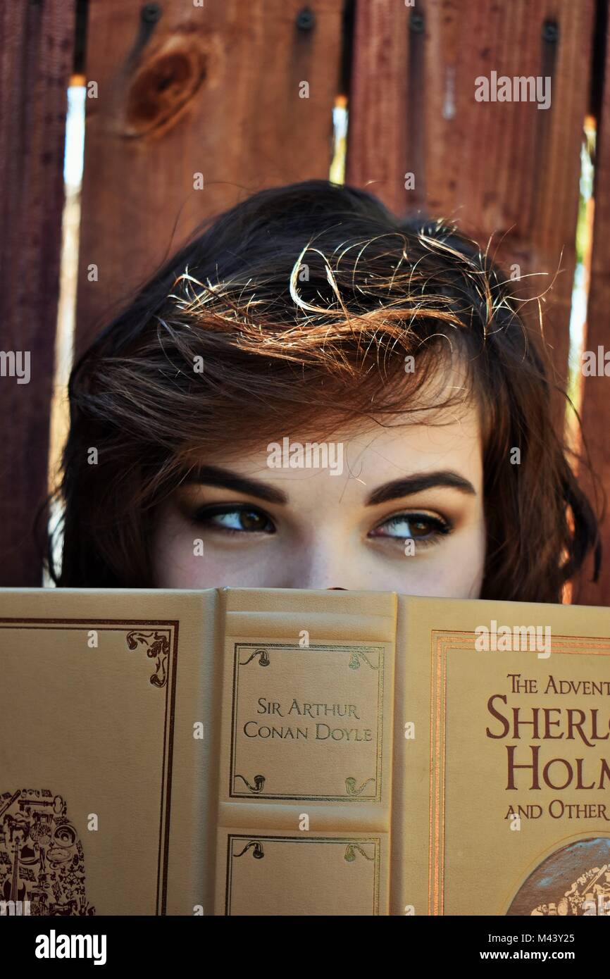 Young Women Dramatically Looking To The Right Holding Mystery Book Stock Photo