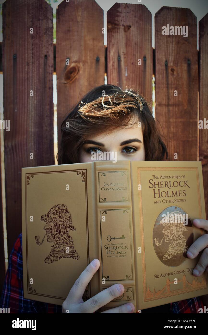 Young Women Dramatically Looking At The Camera Holding Mystery Book Stock Photo