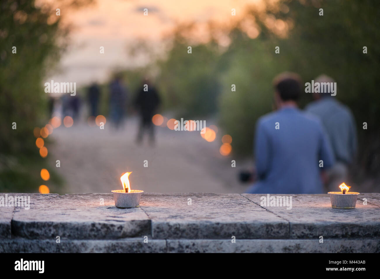 Macro shot of lit candle burning with soft glowing flame and smoke on romantic sunset background