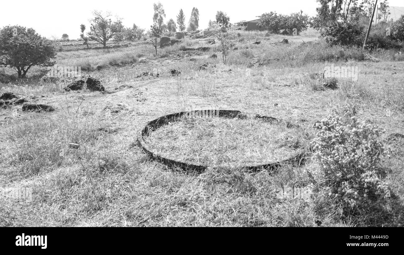 Black and white image of a concrete pipe cut across and laid waste among the brush in a rural area. Stock Photo
