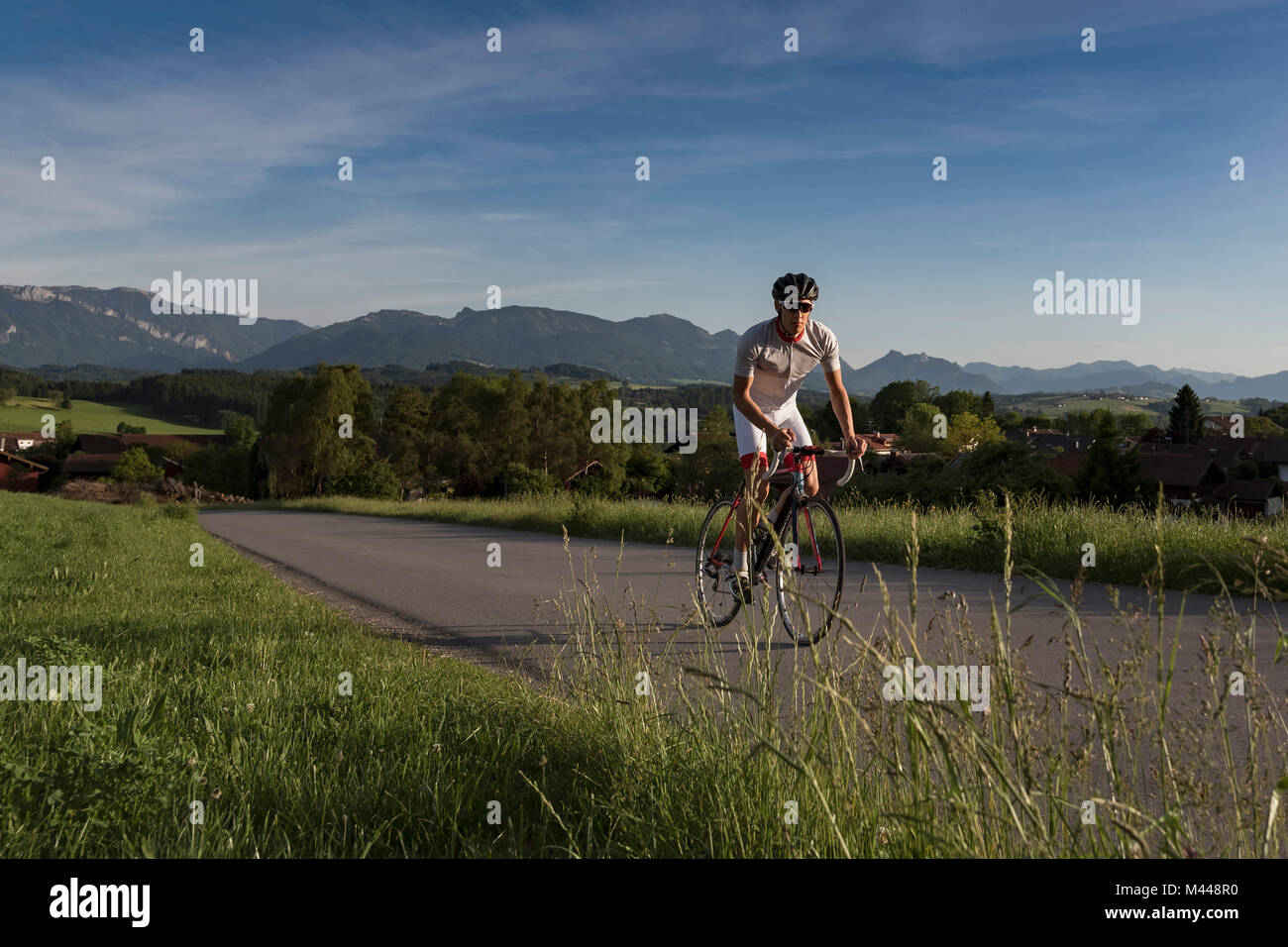 Young male cyclist cycling up rural road Stock Photo