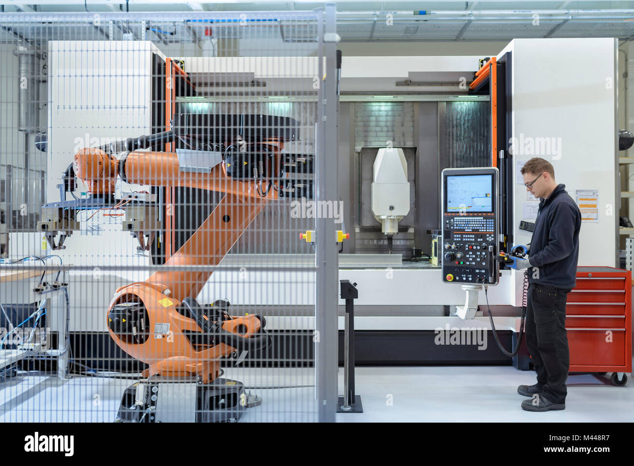 Robotics engineer operating robot aided CNC machine in robotics research facility Stock Photo