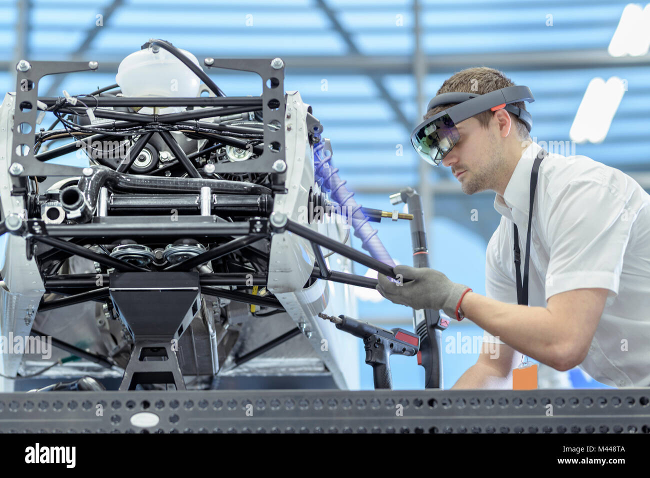 Engineer using augmented reality headset to see parts position on car,  CAD of part, robotics research facility, composite image Stock Photo