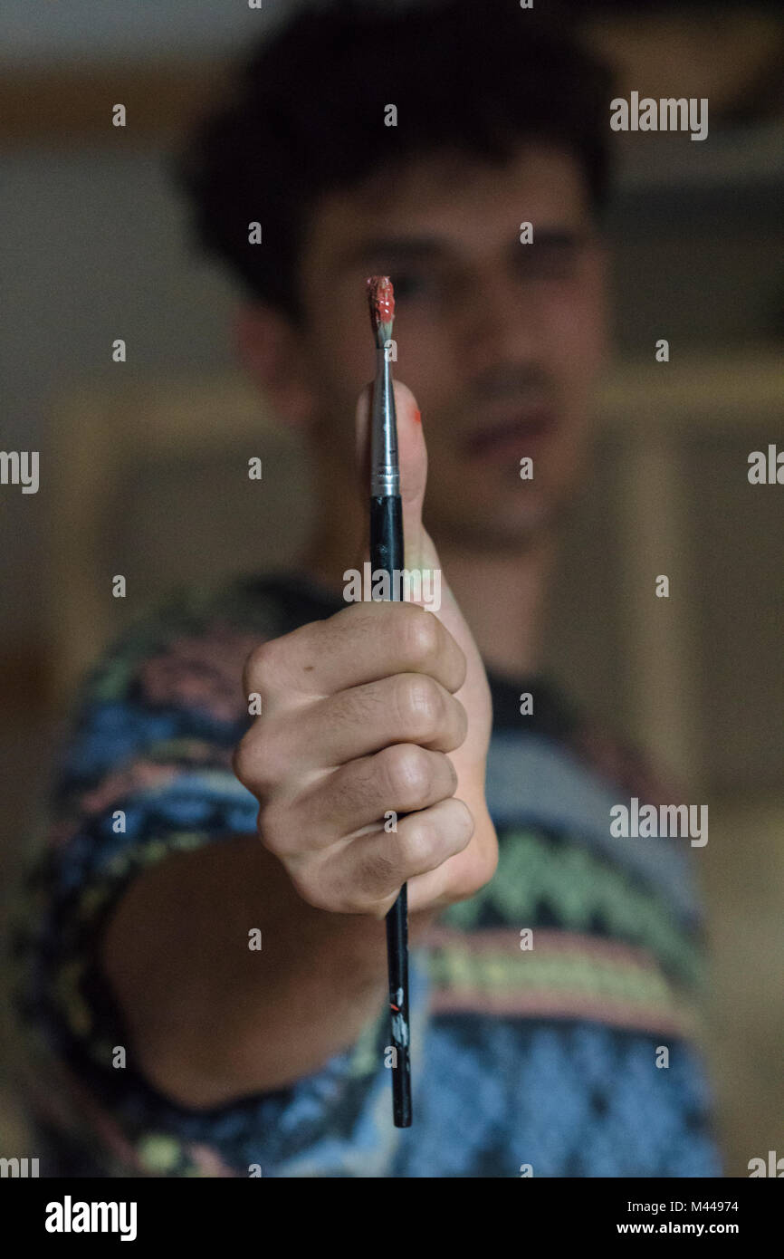 Male artist holding paintbrush in artists studio, close up Stock Photo ...