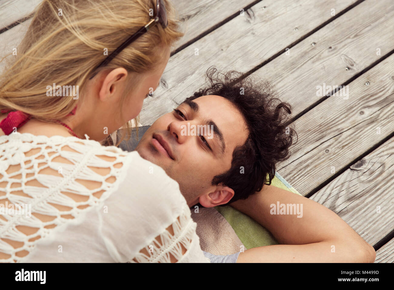 Couple lying face to face on decking Stock Photo