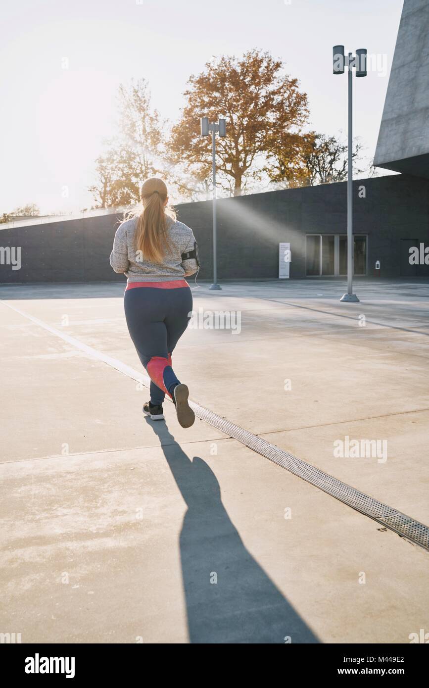 Curvaceous young female runner running, rear view Stock Photo - Alamy