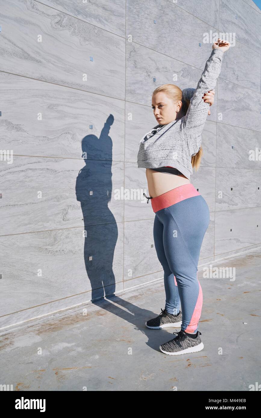 Curvaceous young woman training, stretching arms Stock Photo