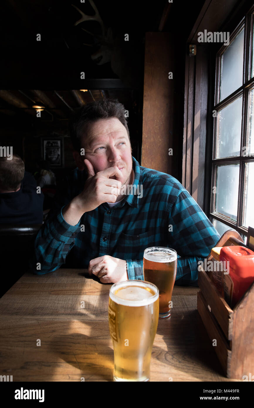 Man having beer looking out of window Stock Photo
