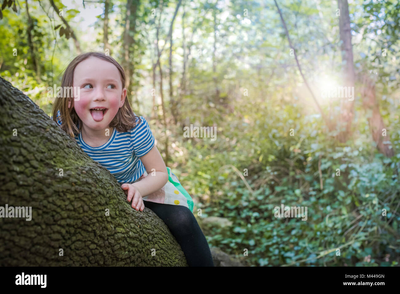 Mischievous girl on tree trunk Stock Photo