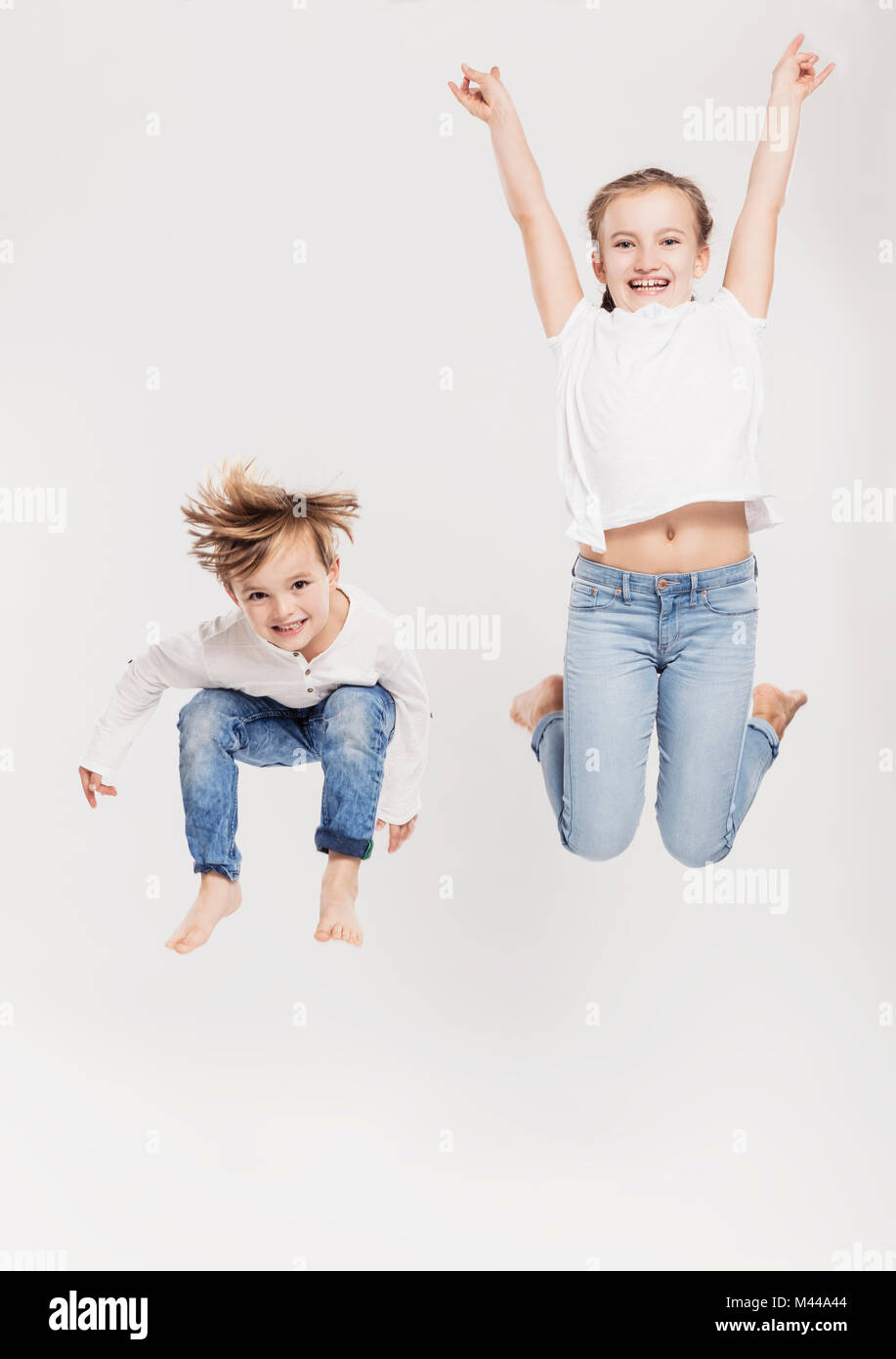 Portrait of brother and sister leaping in air Stock Photo