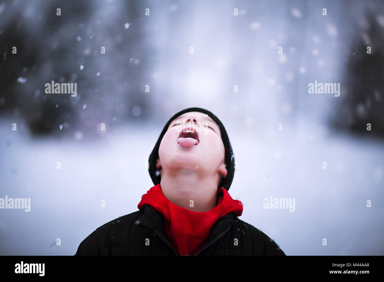 Portrait of boy catching falling snow on tongue Stock Photo