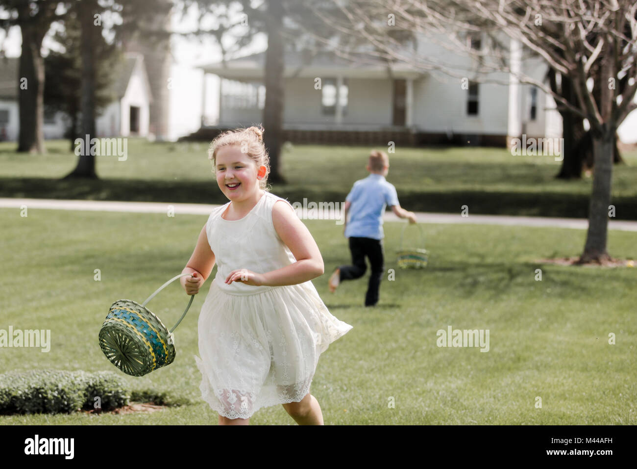 Girl and boy outdoors, holding Easter baskets, on Easter egg hunt Stock Photo