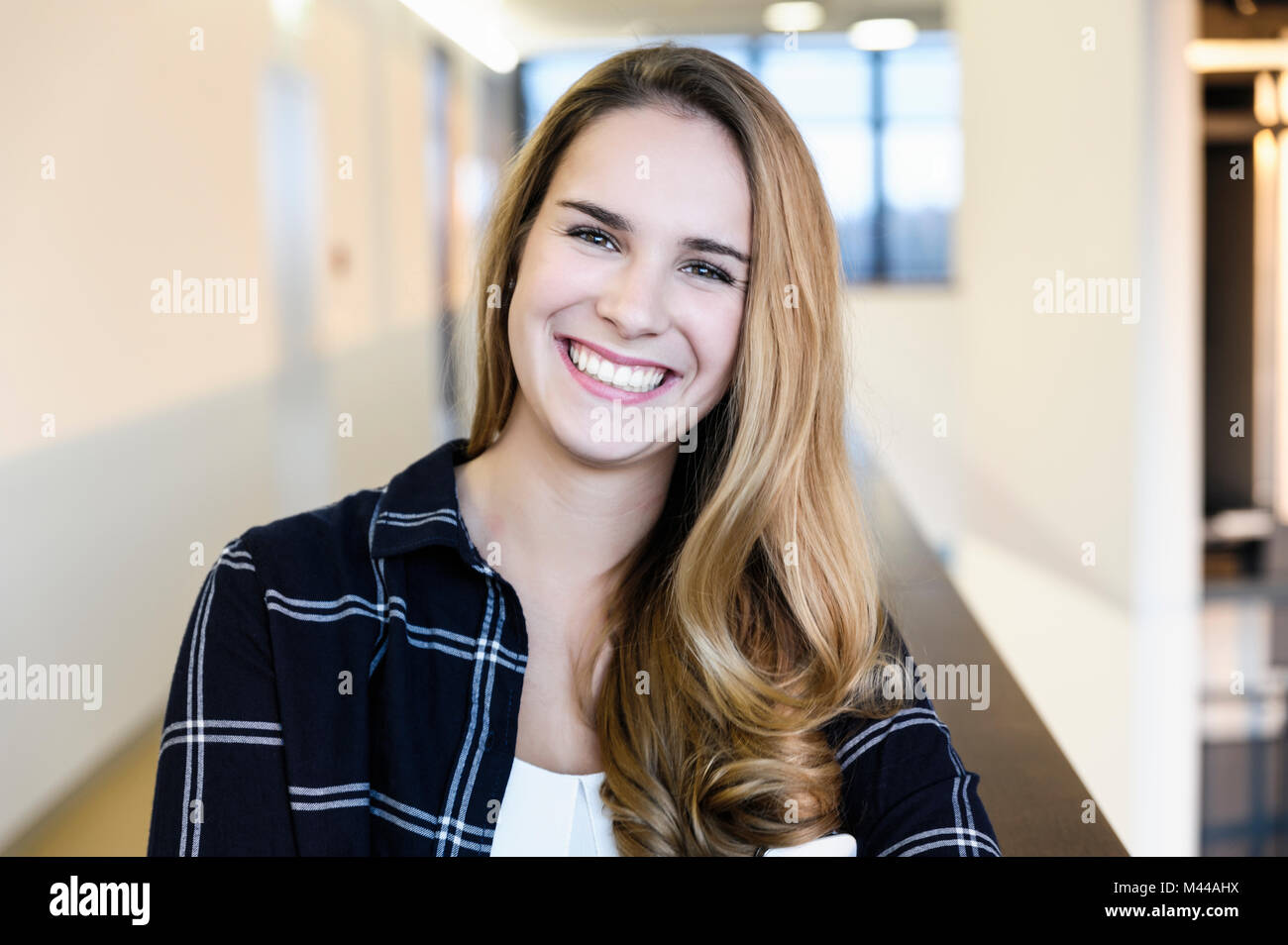 Portrait of young happy businesswoman in office corridor, head and shoulders Stock Photo