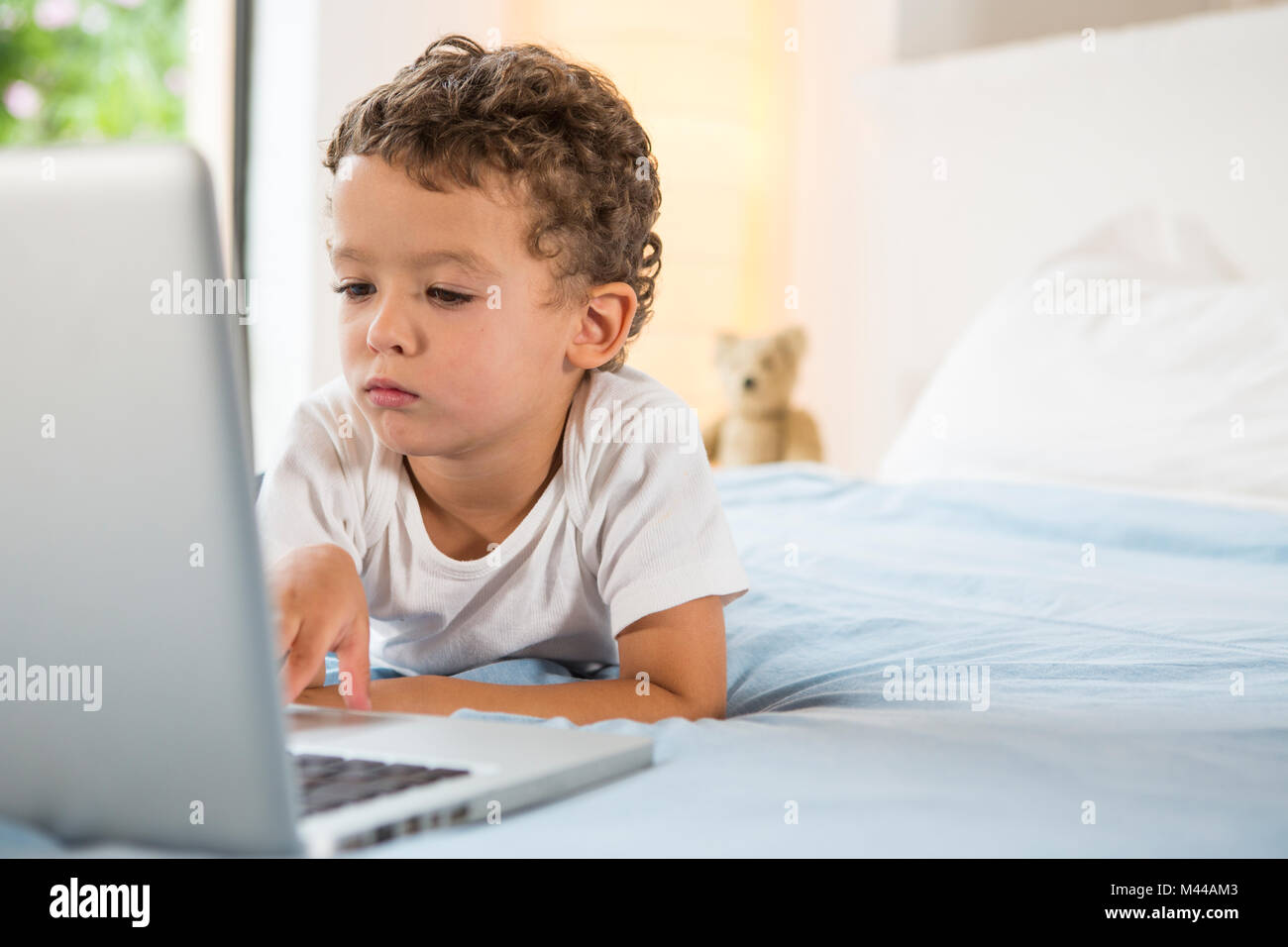 Boy using laptop on bed Stock Photo Alamy