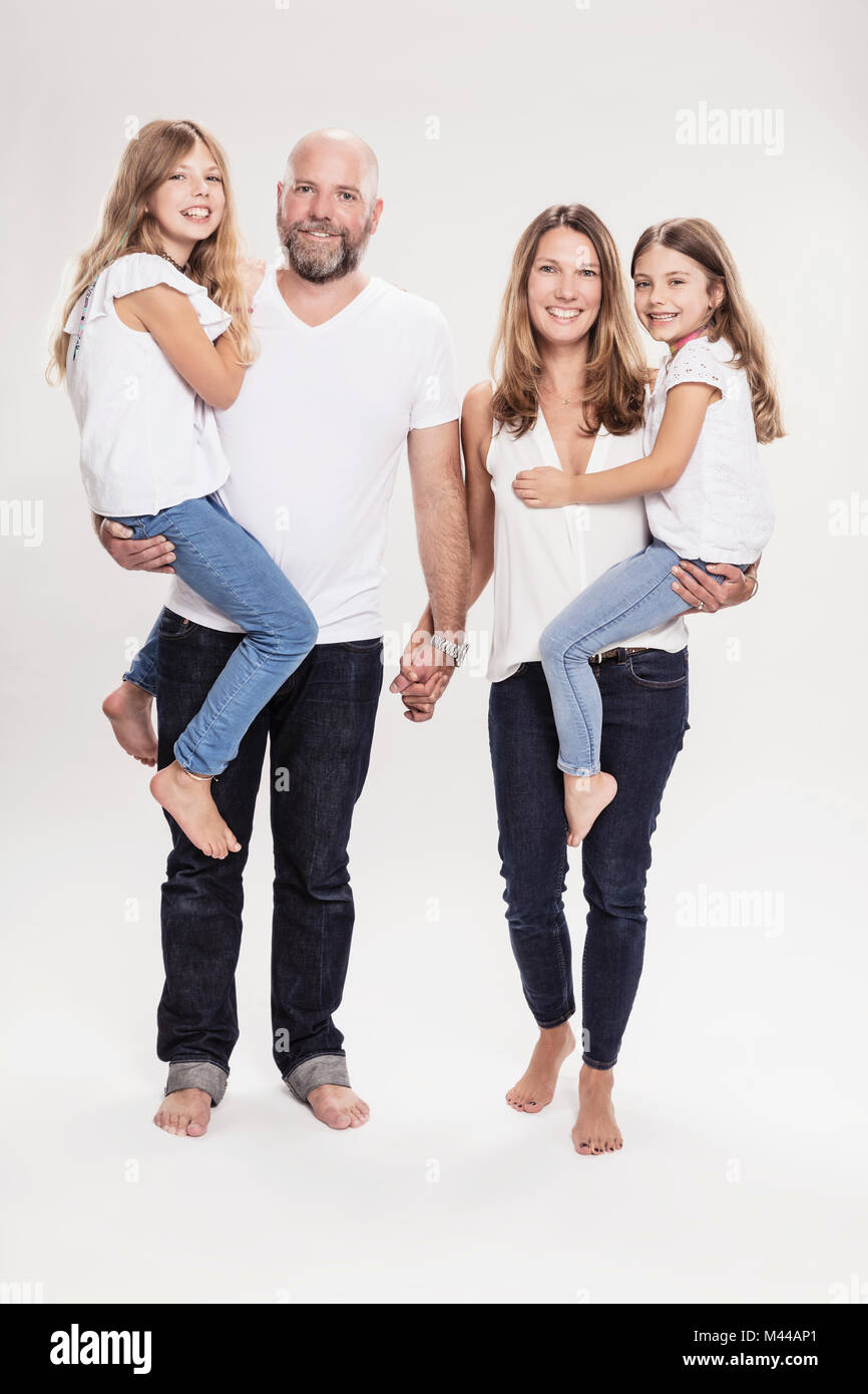 Studio portrait of mature couple carrying two daughters, full length Stock Photo