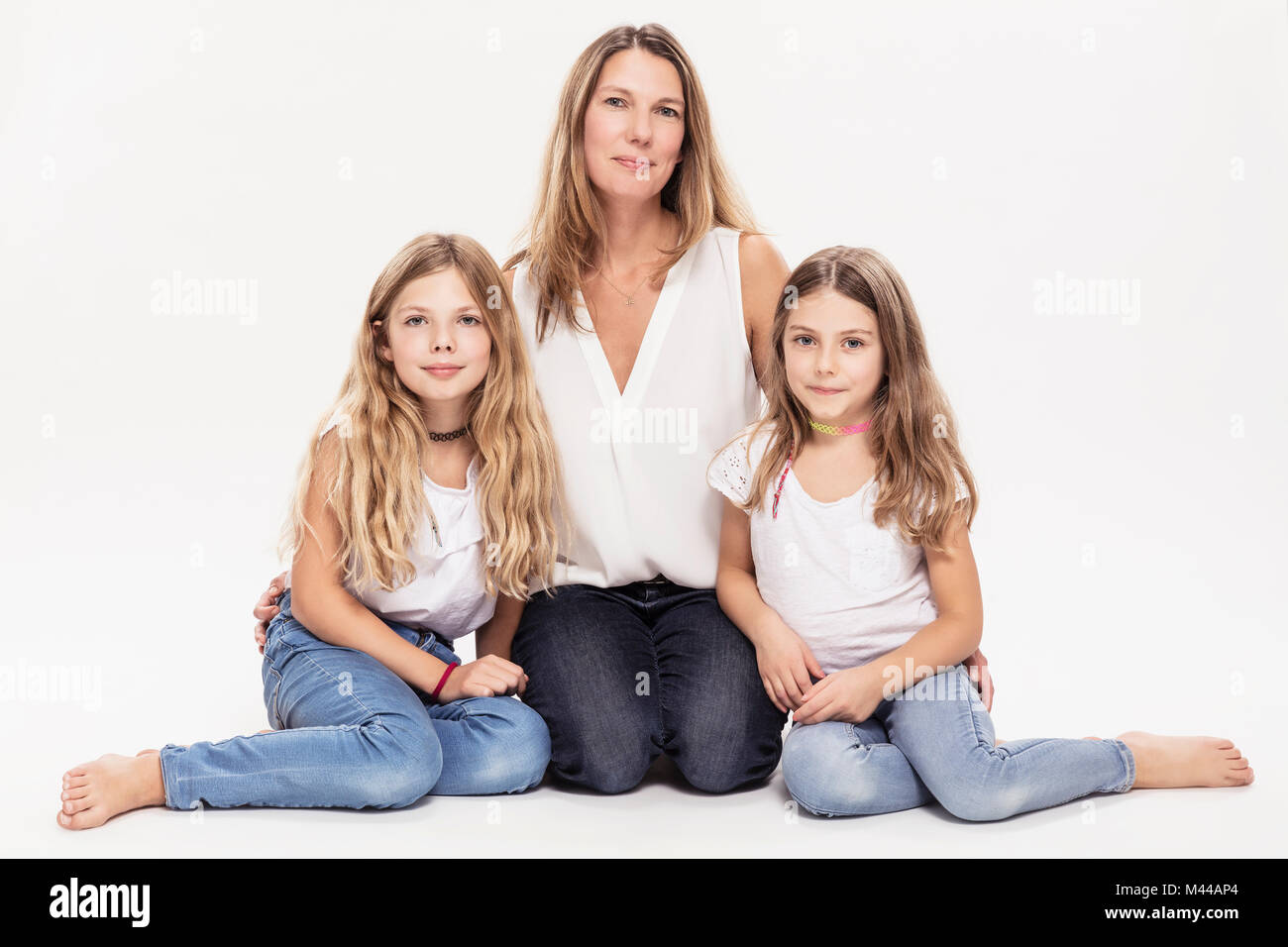 Studio portrait of mature woman with two daughters sitting on floor Stock Photo