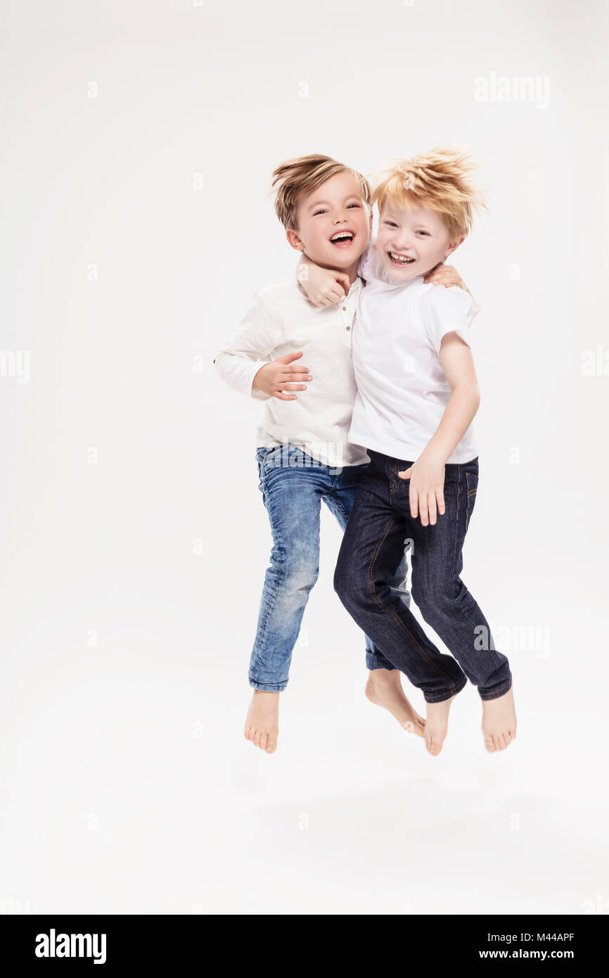 Studio portrait of two boys jumping mid air, full length Stock Photo