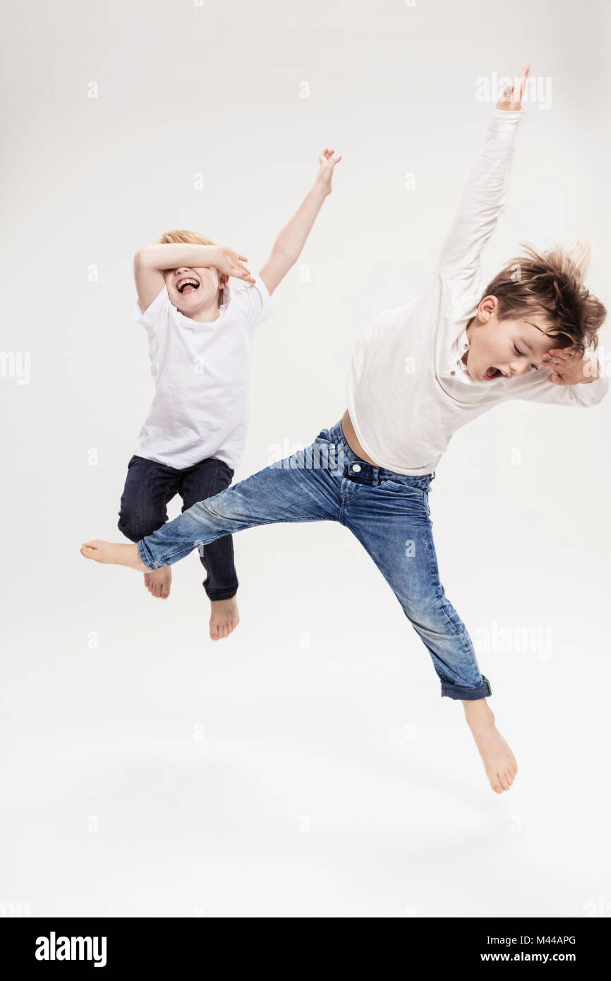 Studio portrait of two boys having fun jumping mid air, full length Stock Photo