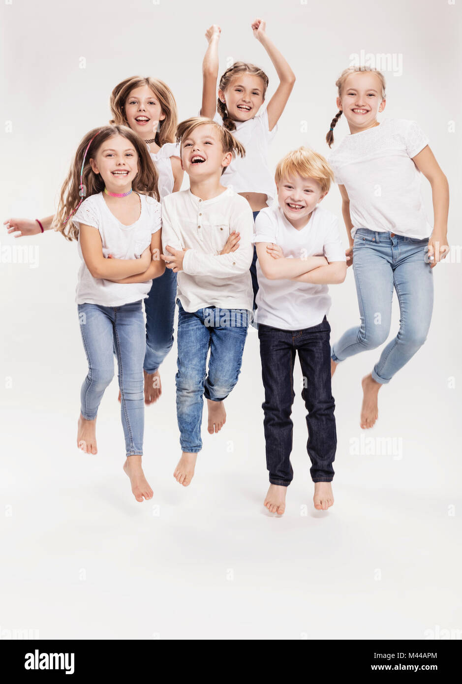 Studio portrait of two boys and four girls having fun jumping mid air, full length Stock Photo