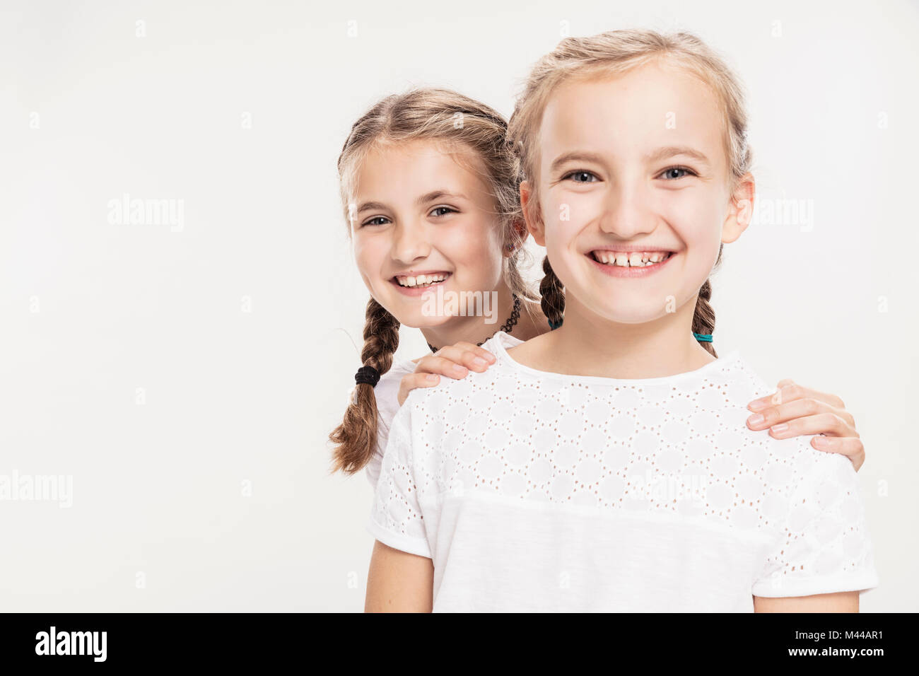 Studio portrait of two smiling girls, head and shoulders Stock Photo