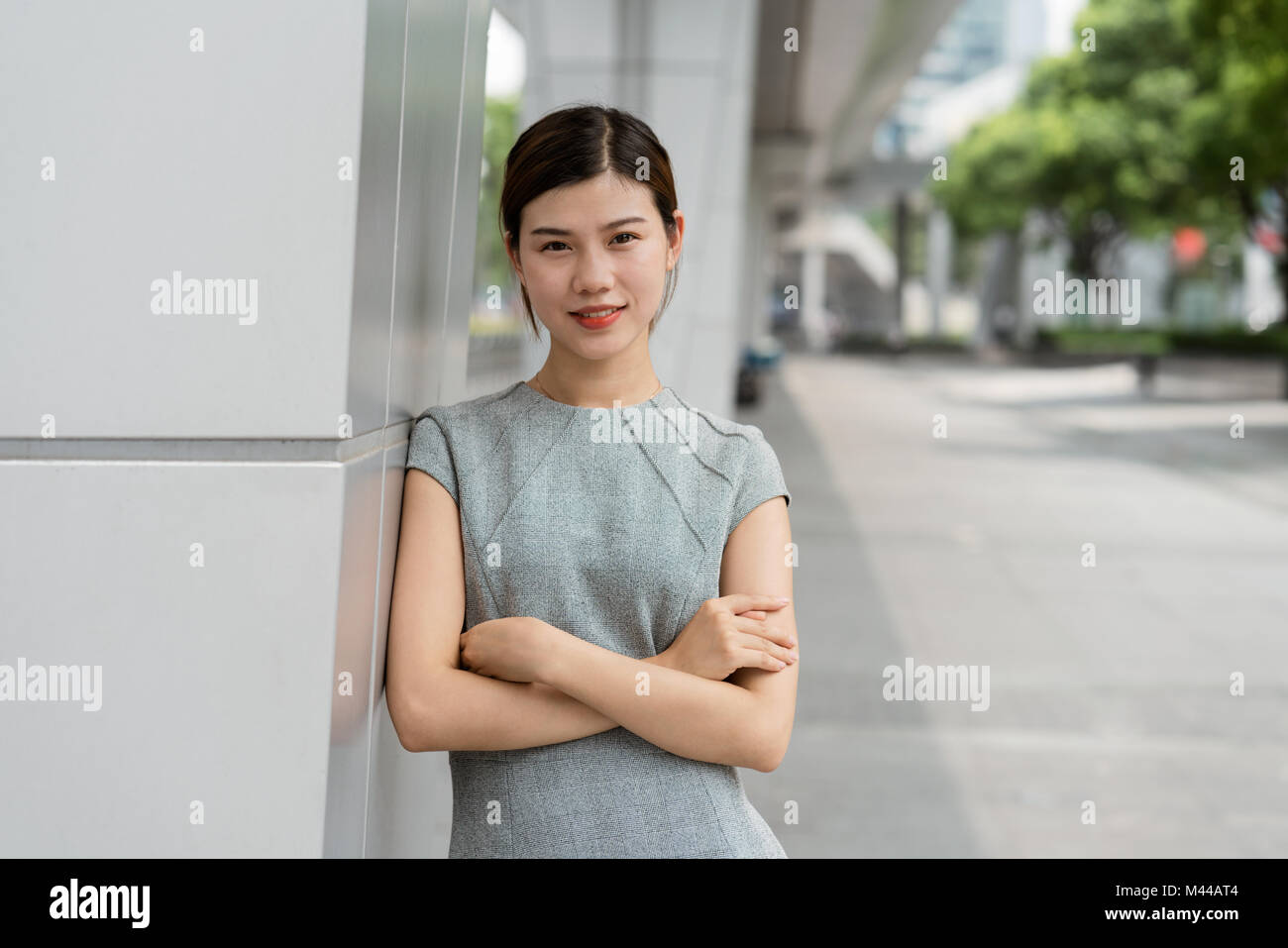 Portrait of young businesswoman leaning against wall in city, Shanghai, China Stock Photo