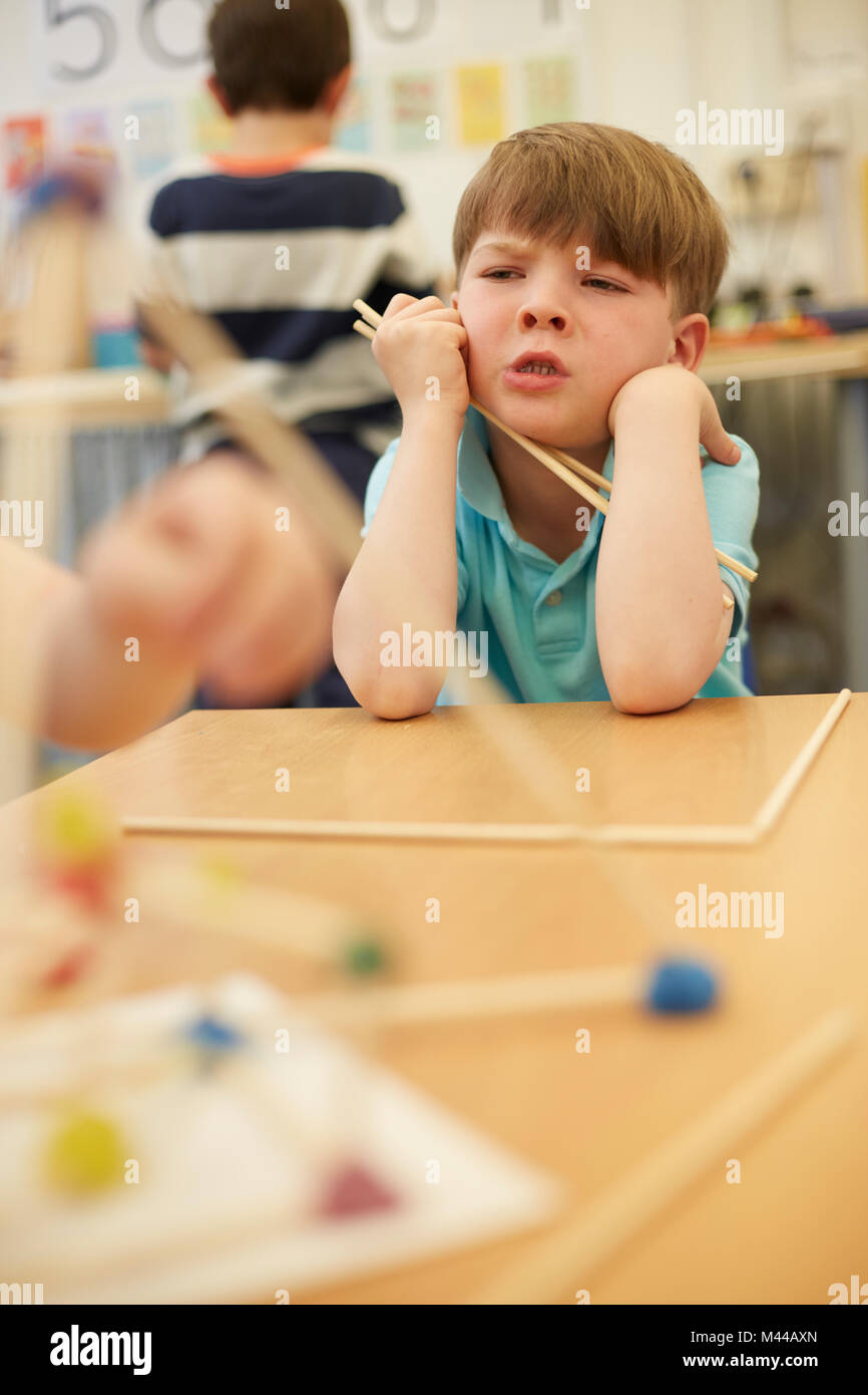 Primary schoolboy with plastic straws on classroom desks Stock Photo