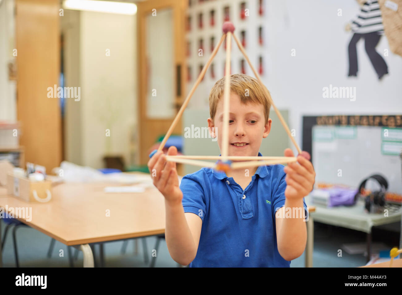 Primary schoolboy holding up plastic straw pyramid in classroom Stock Photo