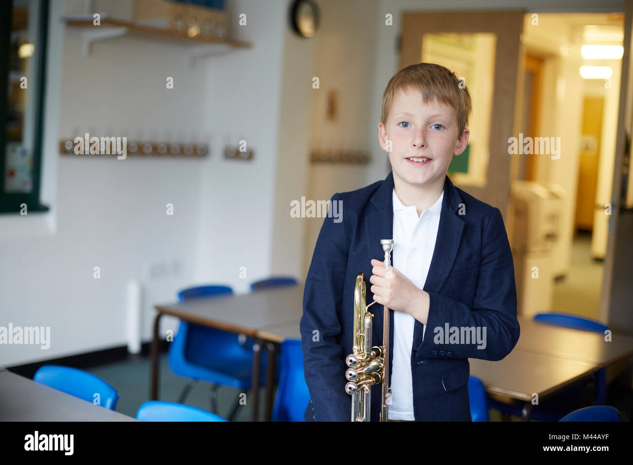 Primary schoolboy holding trumpet in classroom, portrait Stock Photo