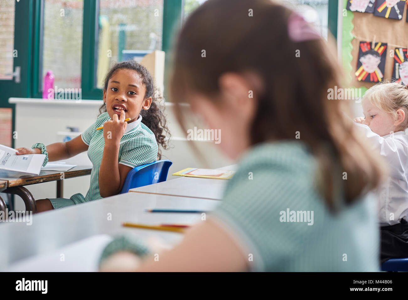 Schoolgirl looking over her shoulder in classroom at primary school Stock Photo