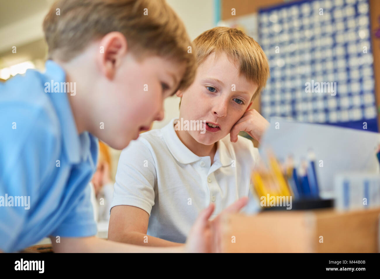 Two schoolboys problem solving in classroom at primary school Stock Photo