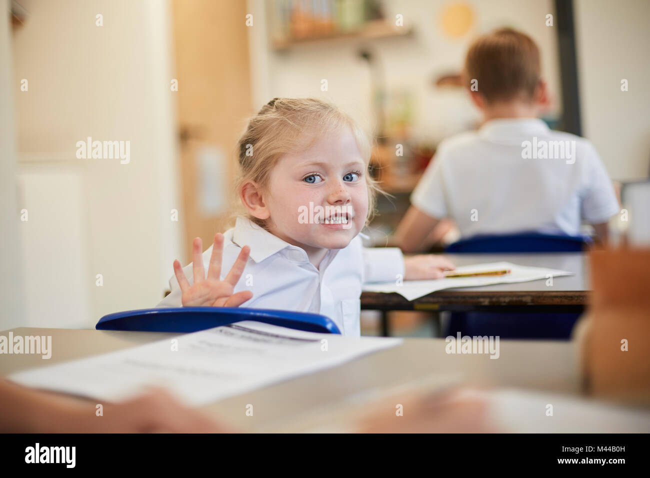 Mischievous schoolgirl in classroom lesson at primary school Stock Photo