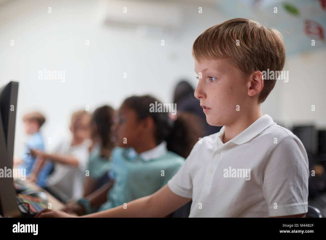 Schoolboy using computer in classroom at primary school Stock Photo