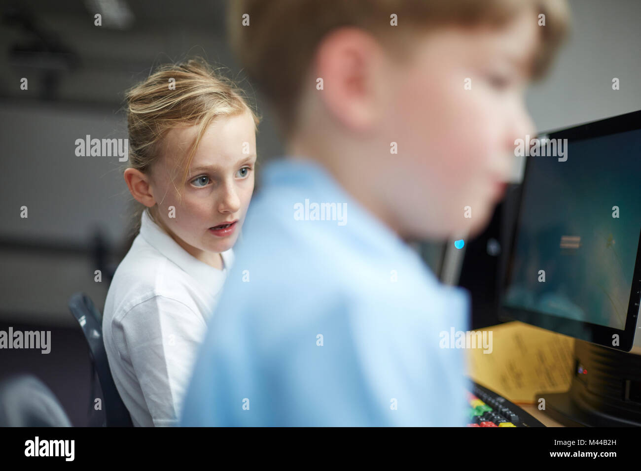 Schoolgirl and boy using computers in classroom at primary school Stock Photo