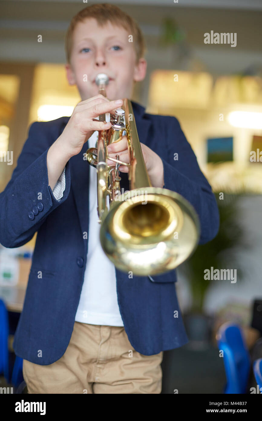 Schoolboy playing trumpet in primary school classroom Stock Photo