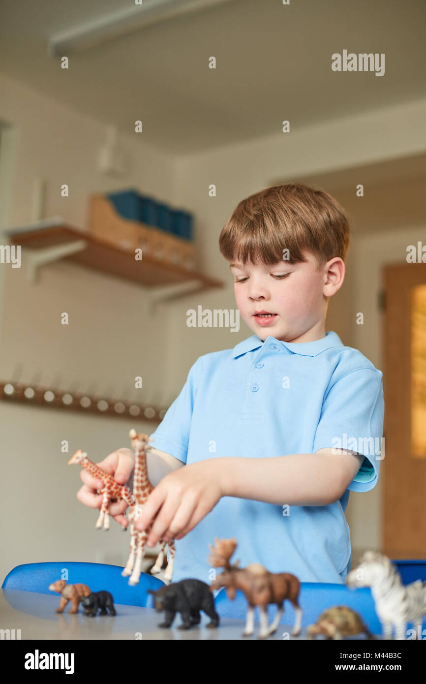 Schoolboy playing with toy animals in classroom at primary school Stock Photo