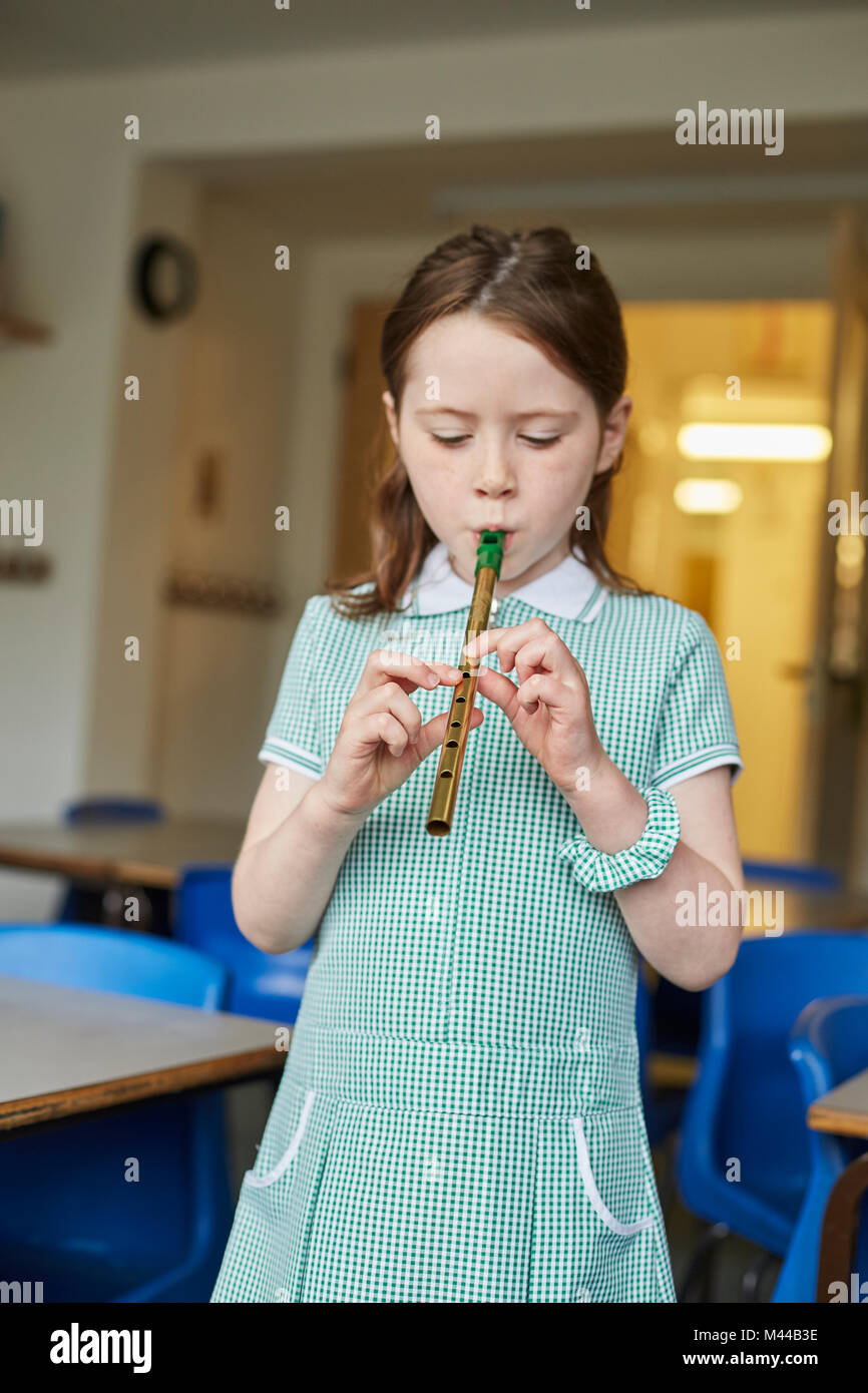 Schoolgirl playing recorder in classroom at primary school Stock Photo
