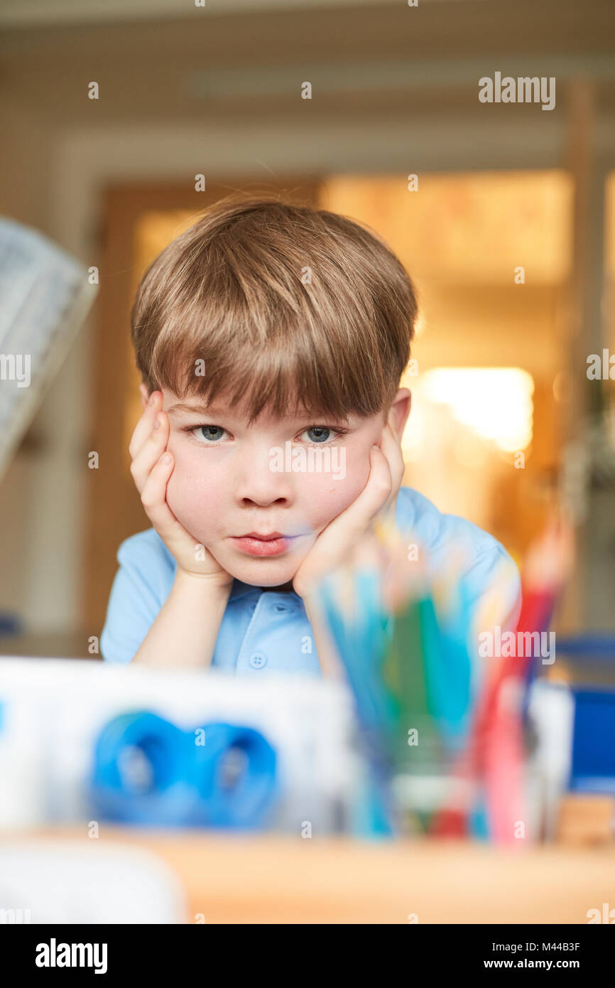 Schoolboy with chin on hands in classroom at primary school, portrait Stock Photo
