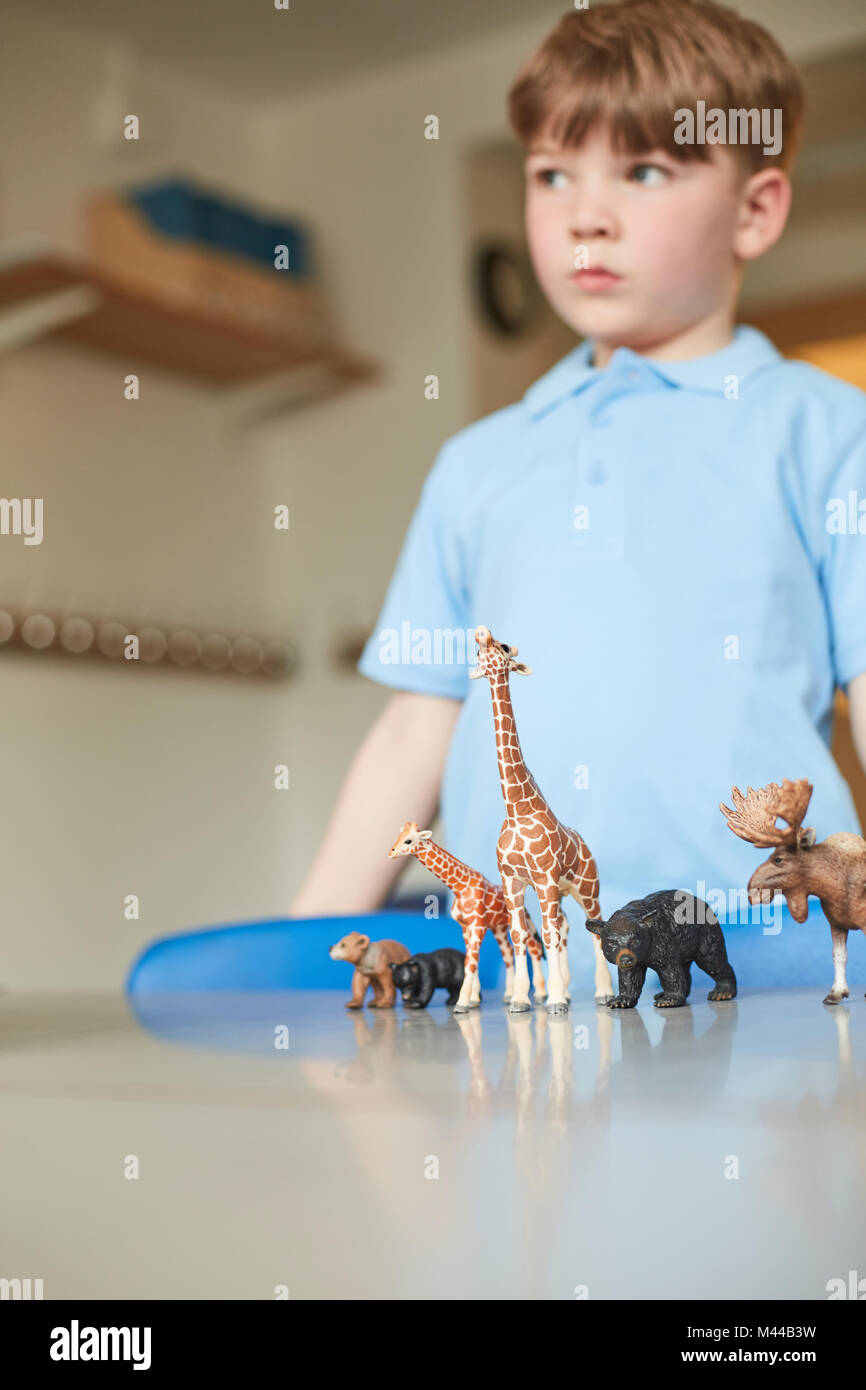 Schoolboy with toy animals in classroom at primary school Stock Photo