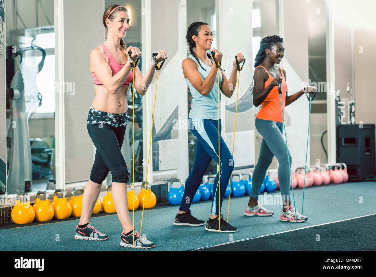 Full length of three fit women exercising with resistance bands  Stock Photo