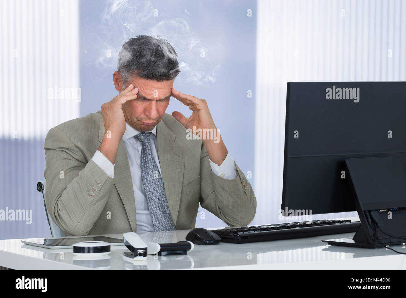 An Angry Stressed Businessman Sitting On Chair At Workplace Stock Photo