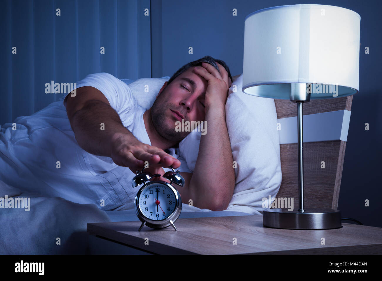 Man Sleeping On Bed Turning Off The Alarm Clock Stock Photo Alamy