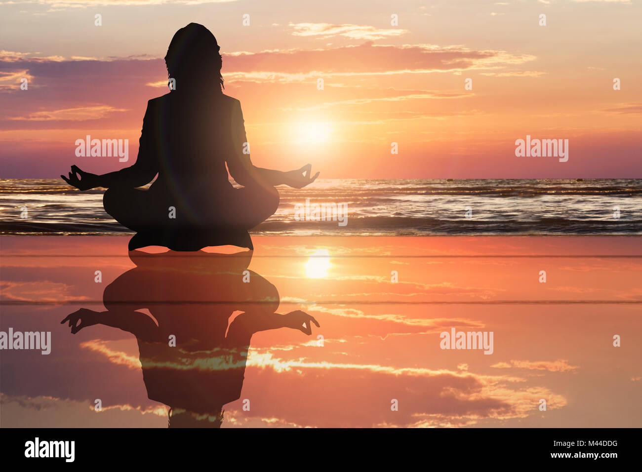 Silhouette Of A Woman Doing Yoga On Beach With Dramatic Sky During Sunset Stock Photo