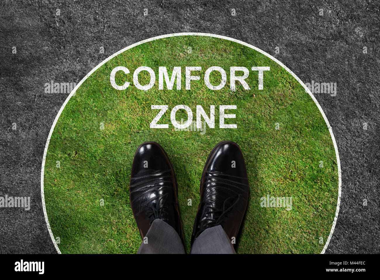 Businessman standing on green and gray carpet with comfort zone text on it Stock Photo